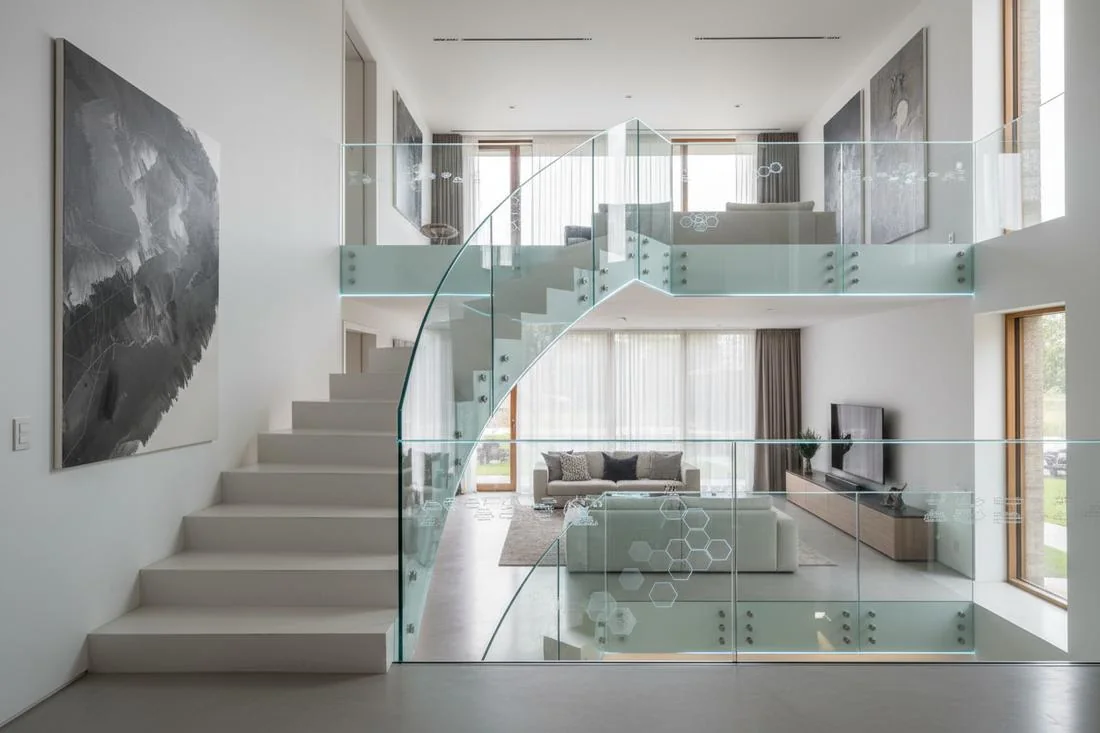 A curved glass railing in a living room, daylight reflected along the panel